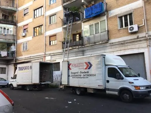 Due mezzi Sorgente Traslochi e l'autoscala al lavoro davanti a un palazzo di Napoli